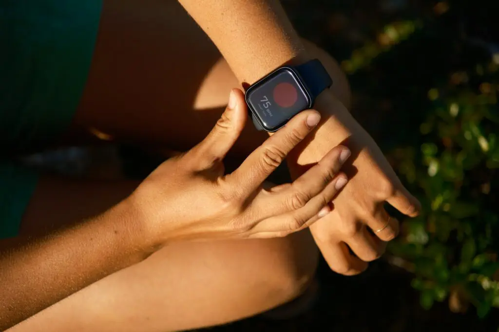 Person adjusting a smartwatch on their wrist outdoors.